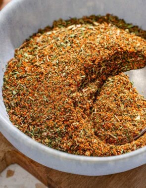 Fish seasoning in a bowl with a spoon on a wooden tray.