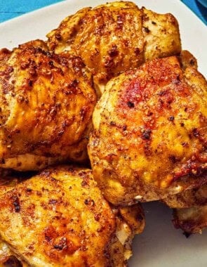 Six air fryer chicken thighs on a plate.