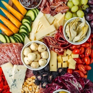 overhead photo of a large antipasto platter with a selection of meats, cheeses, fruits, vegetables and nuts.